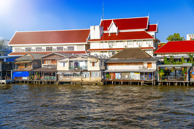 Houses on river against buildings