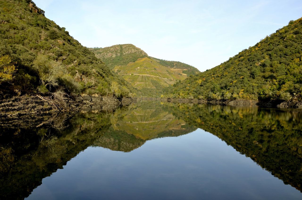 water, reflection, tranquil scene, tranquility, scenics, mountain, lake, beauty in nature, tree, nature, waterfront, standing water, sky, clear sky, idyllic, river, landscape, non-urban scene, calm, mountain range