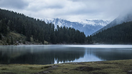 Scenic view of lake and mountains against cloudy sky