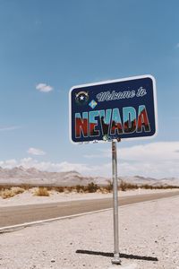 Information sign at roadside against blue sky