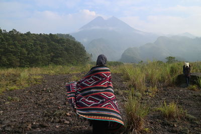 Rear view of woman with scarf standing on land