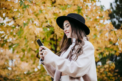 Midsection of woman holding smart phone while standing outdoors