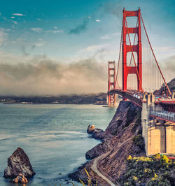 Suspension bridge over sea against sky
