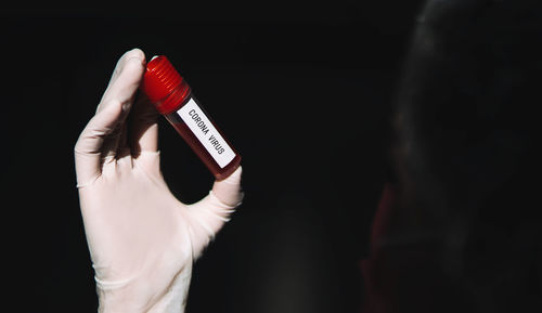 Close-up of hand holding red over black background