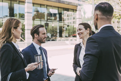 Smiling female entrepreneur talking to colleagues in city