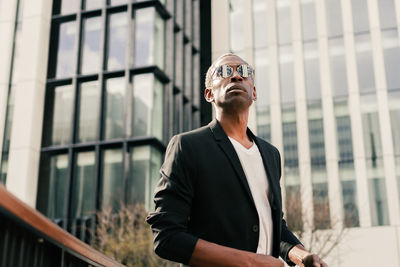 Man wearing sunglasses standing against wall