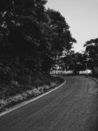 Empty road amidst trees against sky