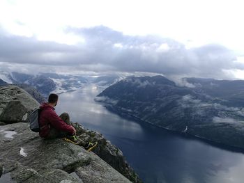 Male hiker sitting on cliff against valley