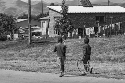 Rear view of people walking on field against buildings