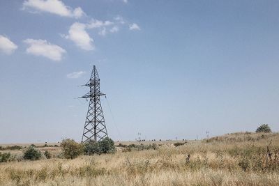 Electricity pylon on field against sky