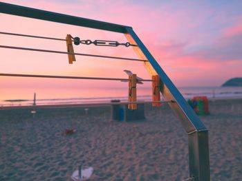 Close-up of clothes hanging on beach against sky during sunset