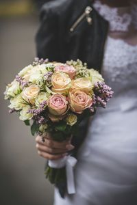 Midsection of bride holding bouquet