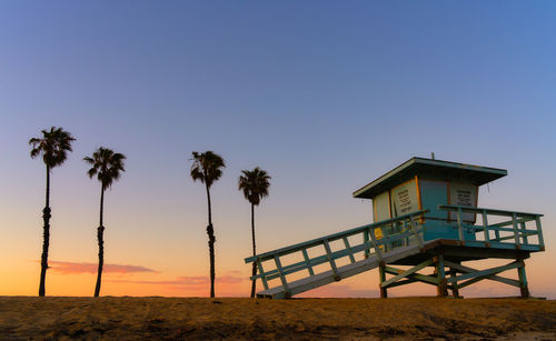 Lifeguard hut on beach against clear sky during sunset