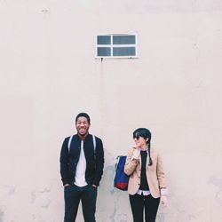 Portrait of young couple standing against wall