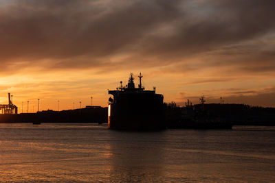 Silhouette ship in sea against sky during sunset