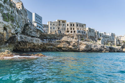 Buildings by sea against clear sky