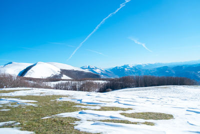 Scenic view of snowcapped mountains against blue sky