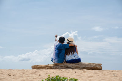Rear view of woman photographing against sky