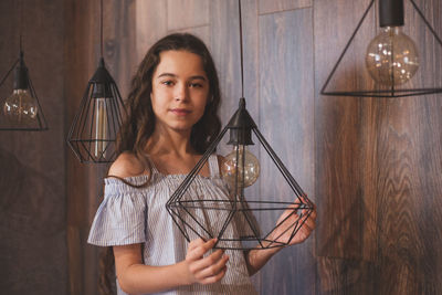 Portrait of young woman holding light bulb