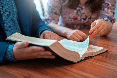 Midsection of woman reading book on table