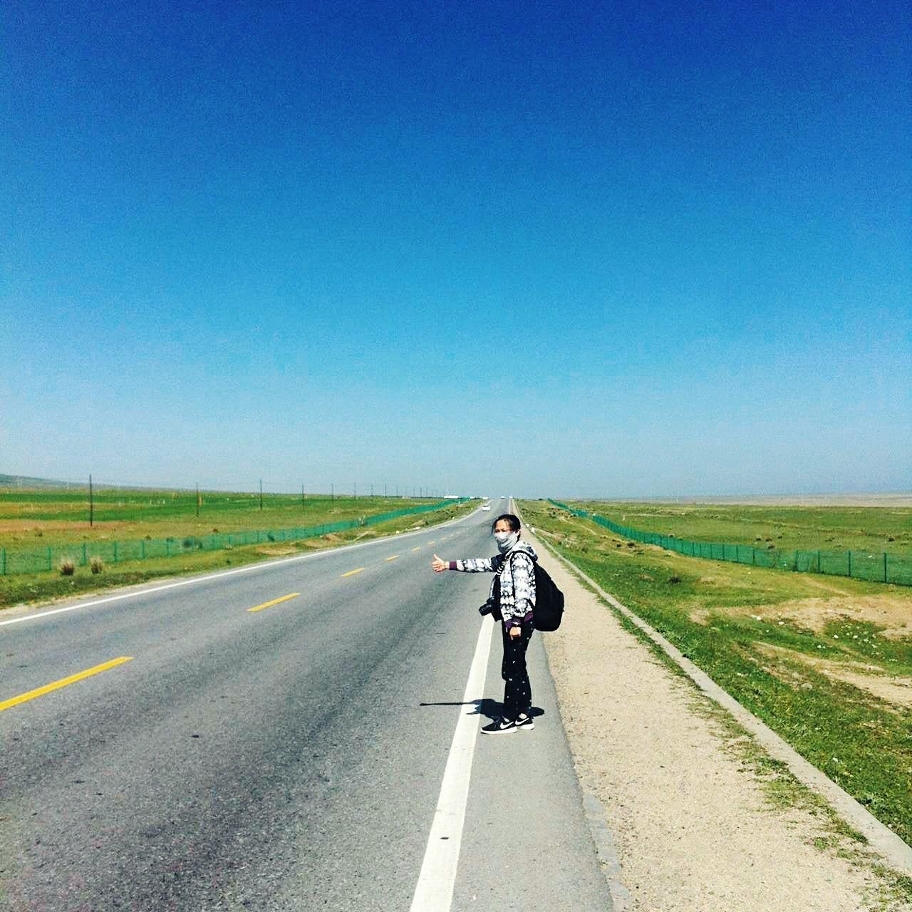 transportation, road, clear sky, copy space, land vehicle, the way forward, mode of transport, road marking, country road, bicycle, riding, landscape, on the move, diminishing perspective, one person, blue, grass, vanishing point, cycling, travel