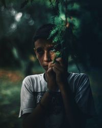 Portrait of young man standing against tree