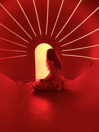 Side view of woman kneeling in red tent