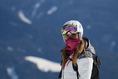 Portrait of young woman wearing skiing helmet during winter
