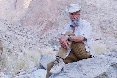 Senior man sitting on rock in the desert 