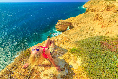 Woman sitting by sea on rock formation at kalbarri national park