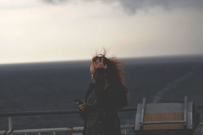 Woman using phone while standing in boat