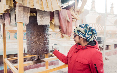 Side view of woman touching bell outdoors