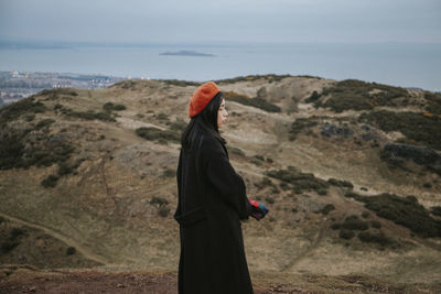 Chinese girl standing on arthur's seat in edinburgh, scotland, uk