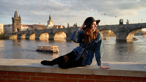 Side view of young woman sitting on bridge