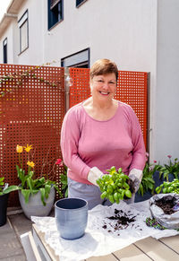 Portrait of smiling woman holding potted plant in restaurant