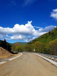 Road leading towards mountains against blue sky