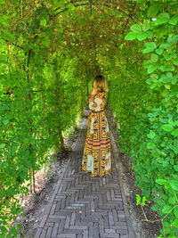 Full length of woman on footpath amidst plants