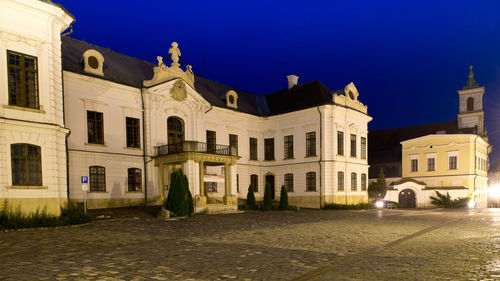 Houses by street against blue sky at night