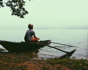 Rear view of man sitting on boat in sea