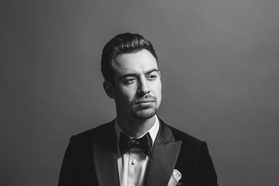 Portrait of young man standing against gray background