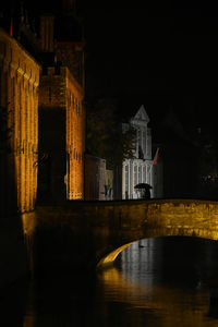 Bridge over river against sky at night