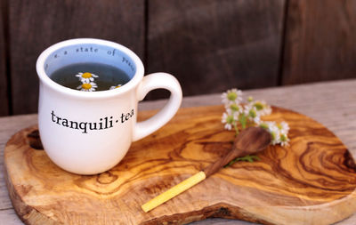 High angle view of cup on cutting board by wooden spoon with flowers