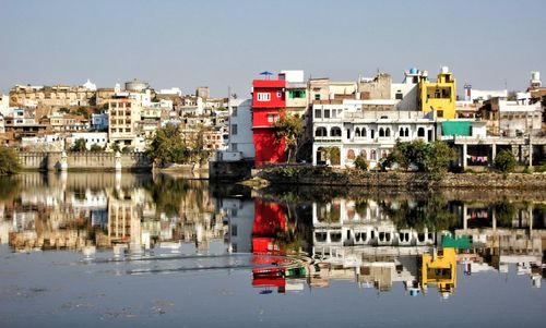 Reflection of buildings in lake against clear sky