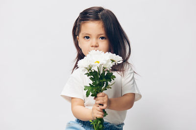 Portrait of young woman holding bouquet against white background