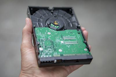 Close-up of person hand holding computer circuit board against gray background