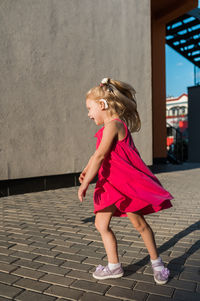 Portrait of young woman standing against wall