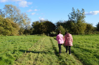 Rear view of women walking on field