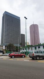 Cars on road by buildings against sky