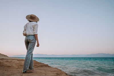 Rear view of man standing at beach against sky