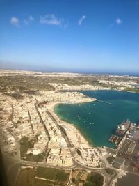 High angle view of city by sea against blue sky